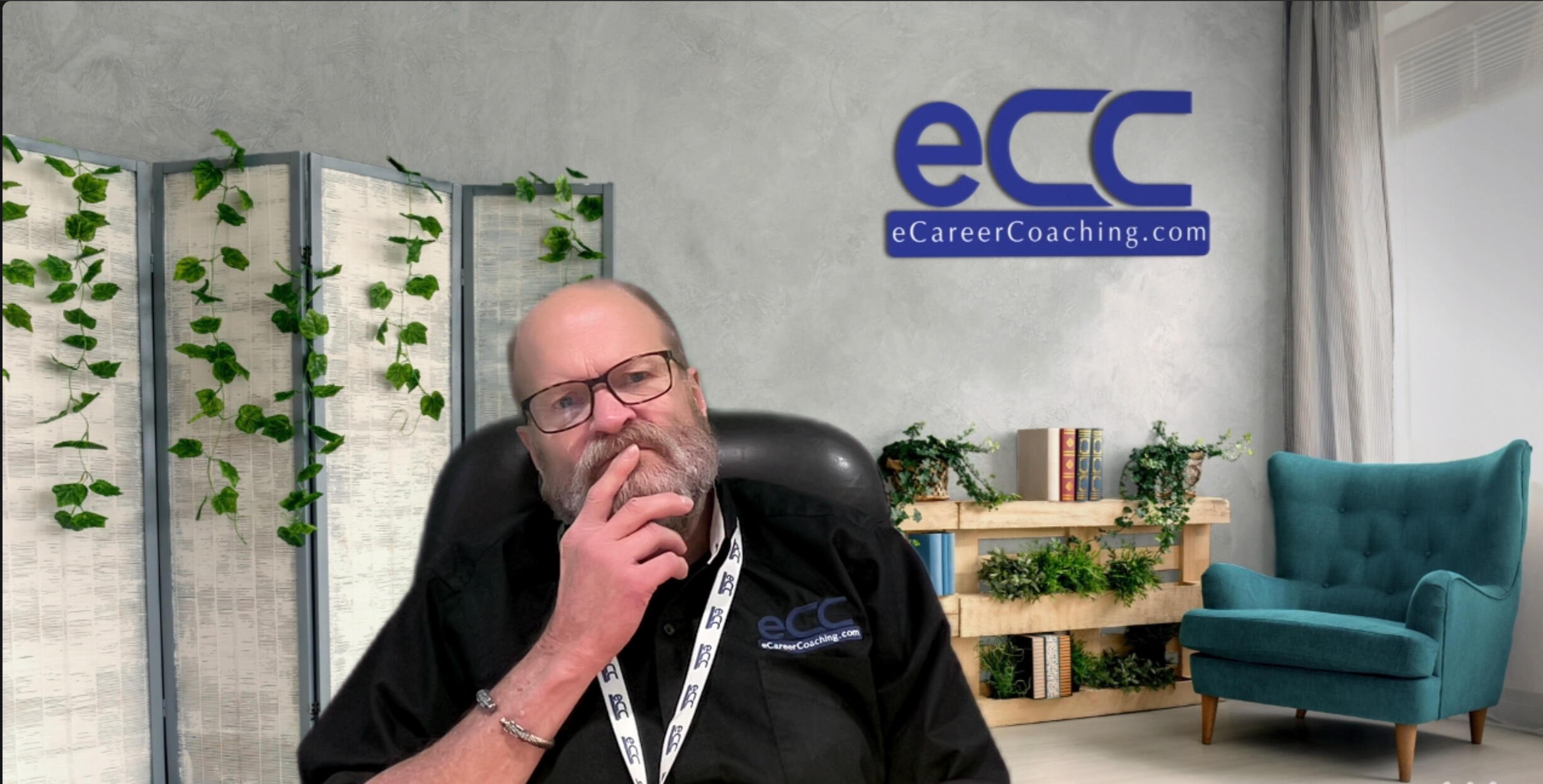 Don Oehlert in his office, thinking. He has his right pointer finger at his mouth while he is thinking. He is wearing glasses with brown frames. There is a green chair in the background and the dark blue eCareerCoaching.com is on the wall over his left sho